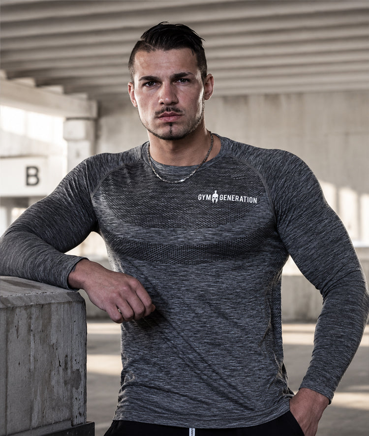 Athlet in grauem Seamless Shirt vor Beton, Schriftzug weiß auf der Brust