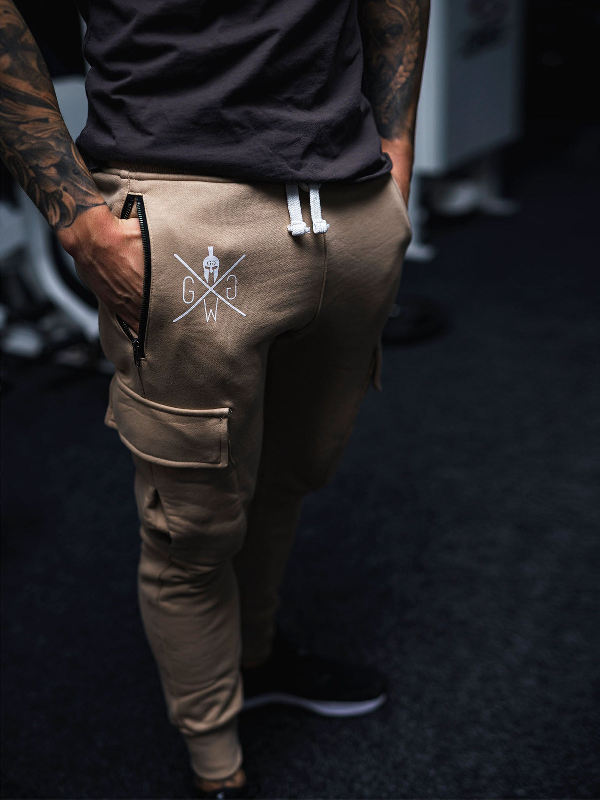 Weißes Logo auf der beigen Cargohose, Nahaufnahme am Model