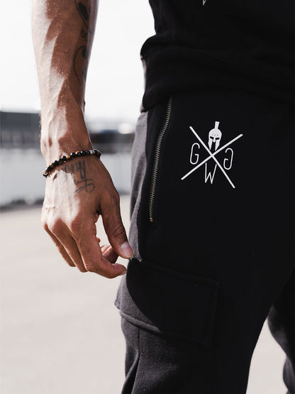 Weißes Logo mit Spartanerhelm auf dem Oberschenkel der schwarzen Hose