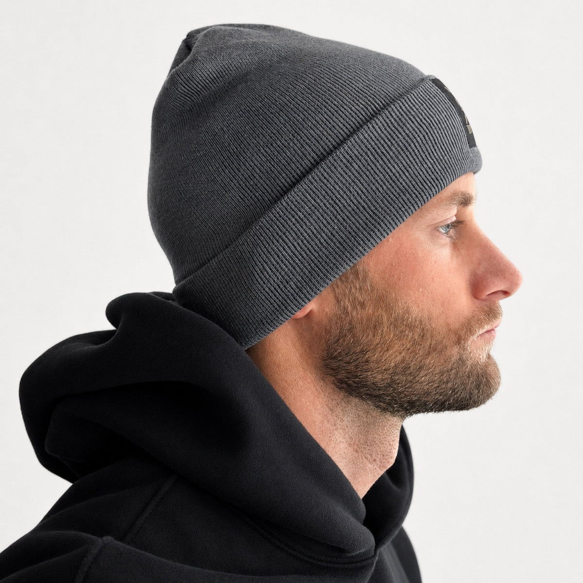 Herren mit grauer Beanie und schwarzem Hoodie im Profil