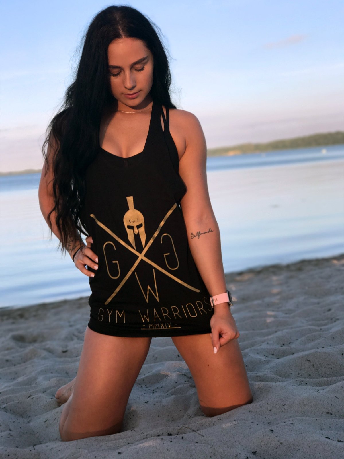 Stringer Tank Top in Schwarz-Gold am Strand getragen