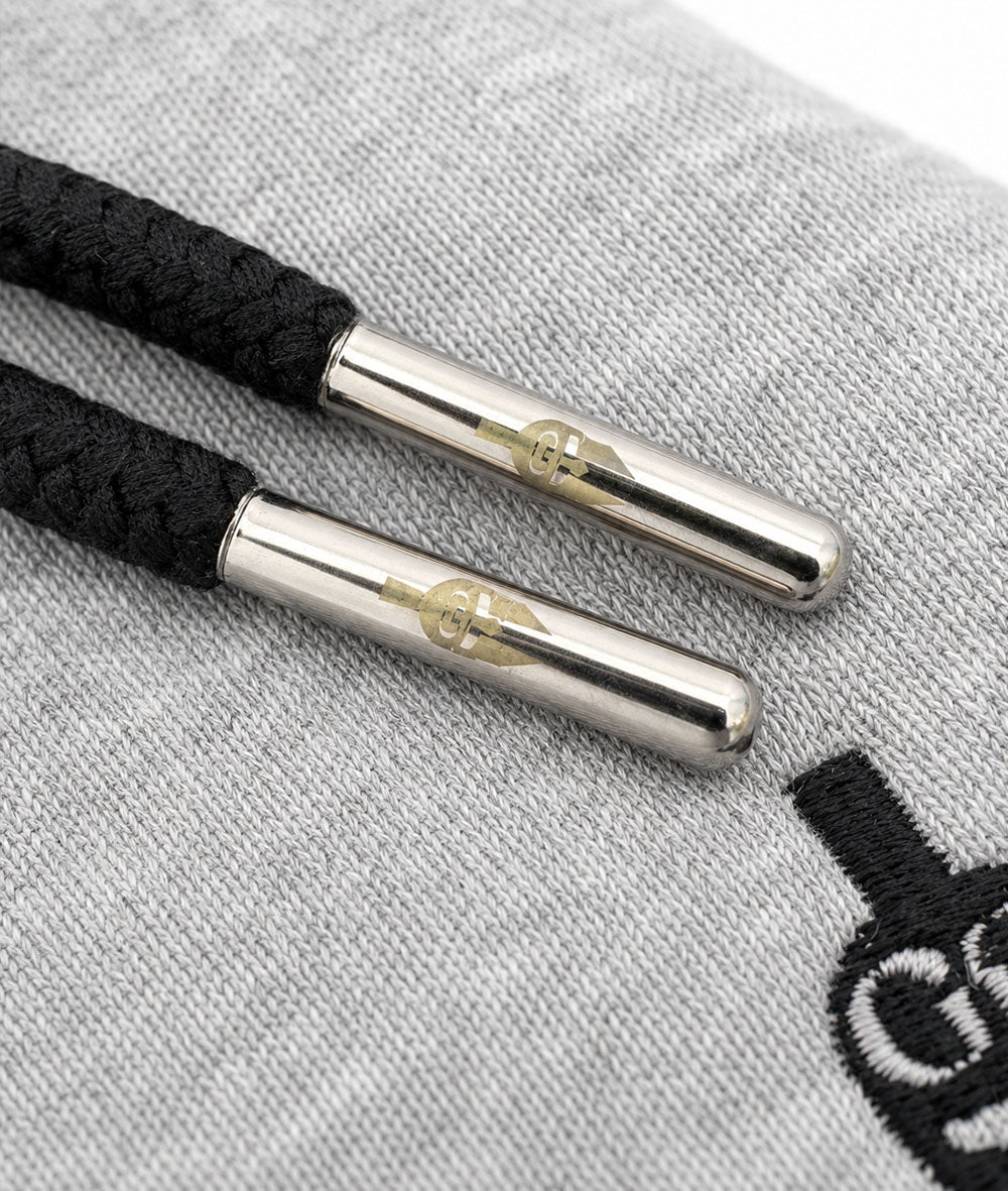 Kordeln mit gravierten Silberkappen auf grauem Sweatstoff