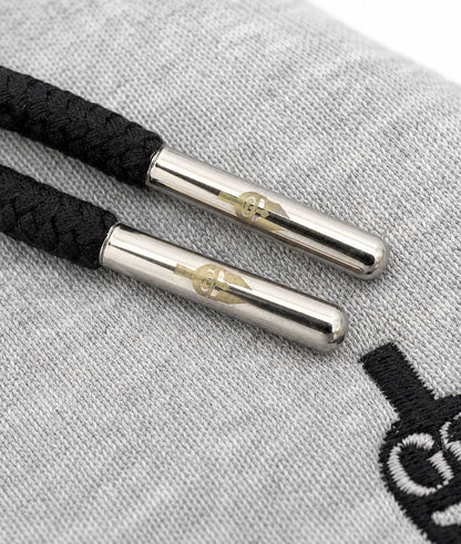 Kordeln mit gravierten Silberkappen auf grauem Sweatstoff