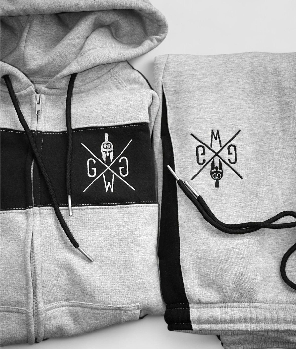 Schwarzer Kontraststreifen mit gesticktem Logo auf grauem Sweatstoff
