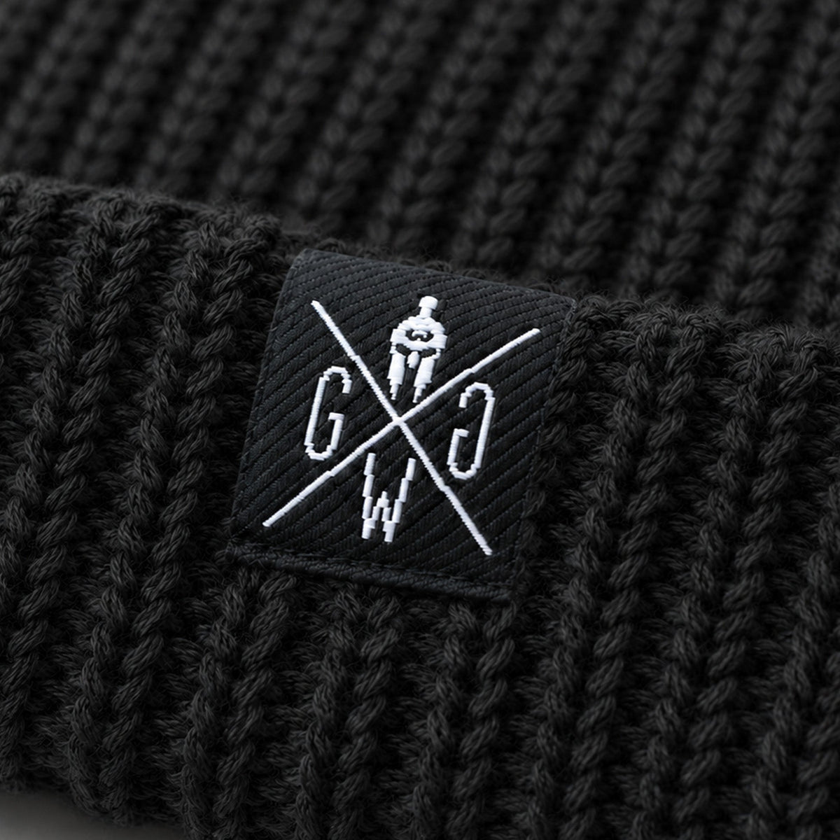 Weißes Logo-Label mit Spartanerhelm auf dem Rippstrick im Detail