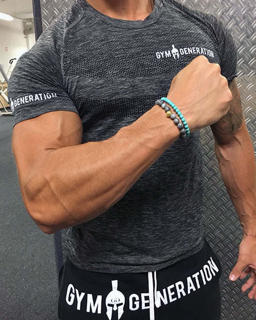 Model im dunkelgrauen Seamless T-Shirt von Gym Generation, eng anliegend mit kurzen Raglanärmeln und weißem Schriftzug