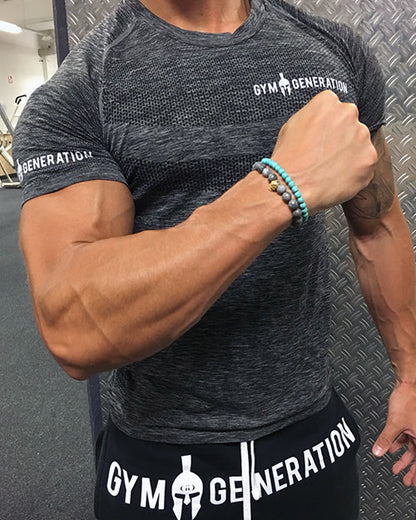 Model im dunkelgrauen Seamless T-Shirt von Gym Generation, eng anliegend mit kurzen Raglanärmeln und weißem Schriftzug