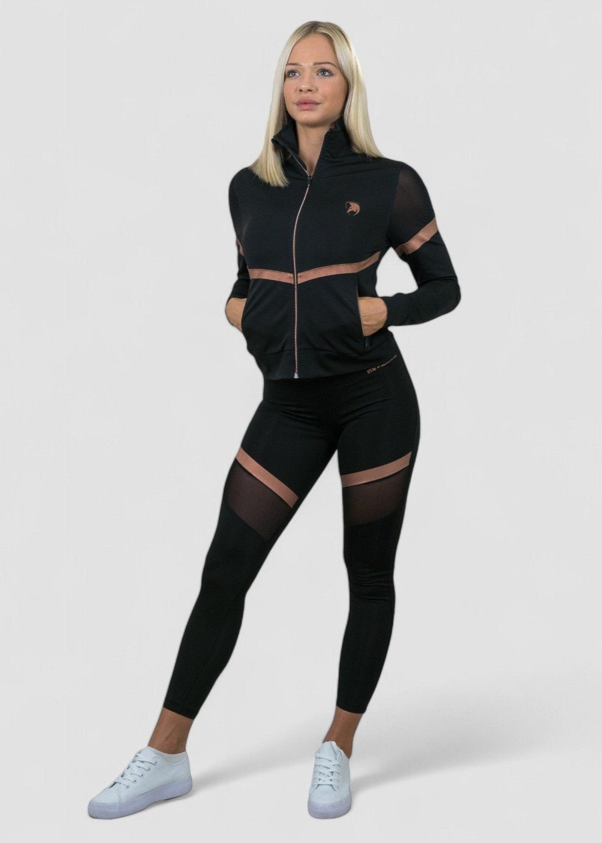 Frau im schwarzen Komplett-Outfit mit Leggings, Hände in den Jackentaschen