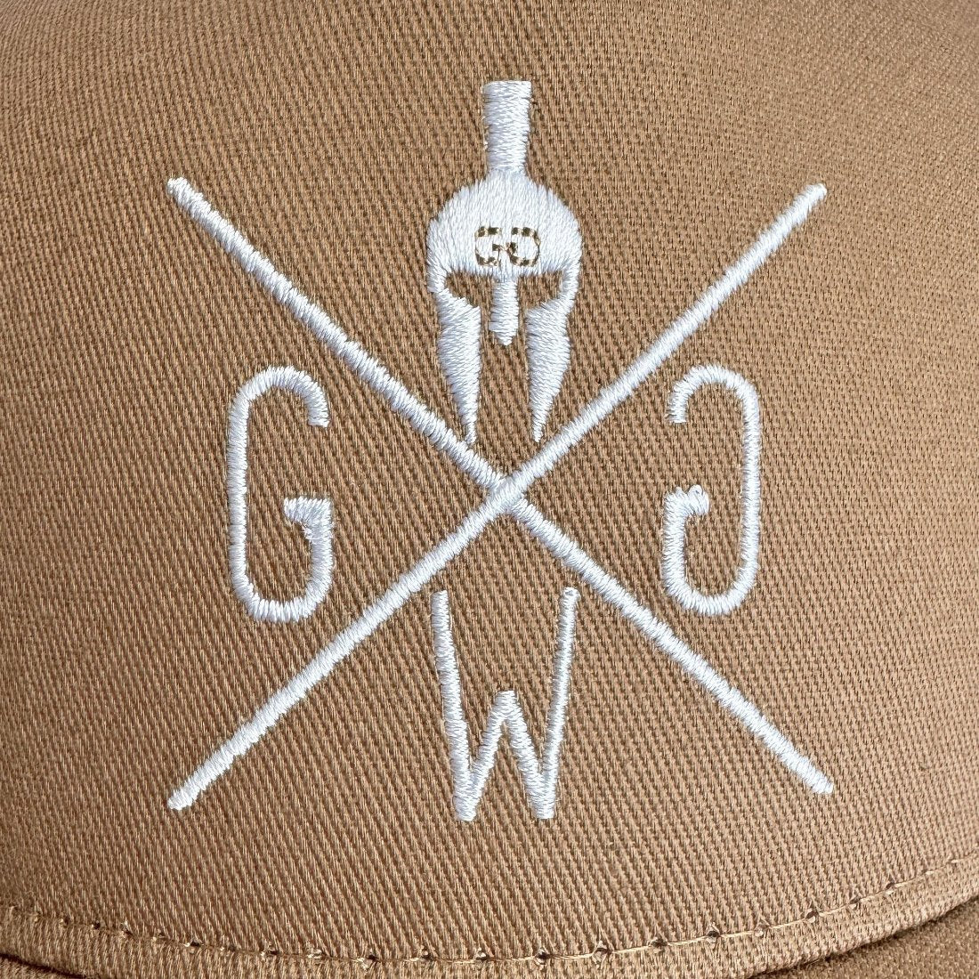 Weiß gesticktes Gym Generation Logo auf beigem Stoff im Detail