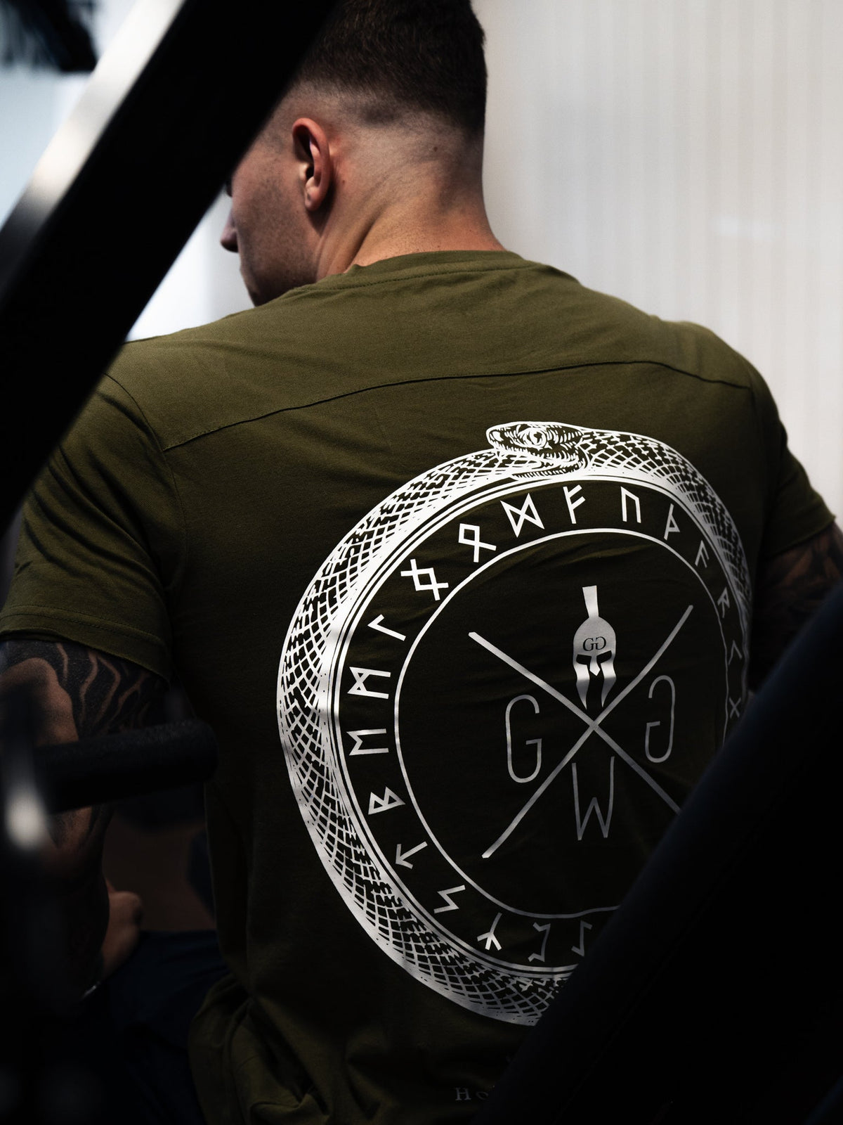 Athlet im oliven Valhalla Shirt, Rückenansicht im Fitnessstudio